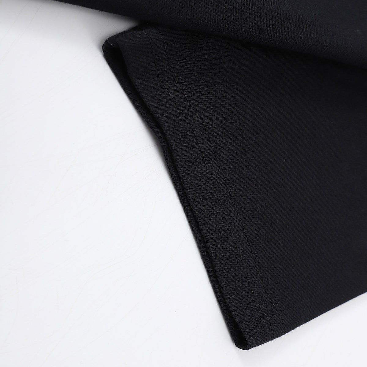Close-up of the sleeve hem and bottom hem stitching on the black Solstice Graphic T-Shirt